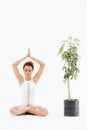 African woman practicing lotus yoga pose near tree in pot Royalty Free Stock Photo