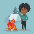 African woman roasting marshmallow over campfire.