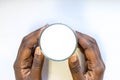 African Woman`s Hand holding glass of warm fresh milk on white background. Top view food and drink for healthy nutrition concept.