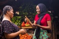 African woman selling in a local food market gives a thumbs up to a customer to confirm successful payment via mobile phone