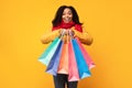 African Woman Shopping In Winter Holding Shopper Bags, Yellow Background