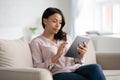 African woman sit on couch using tablet gadget