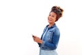 African woman with smart phone standing against white background and laughing