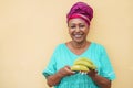 African woman smiling on camera holding a bunch of bananas - Focus on face Royalty Free Stock Photo