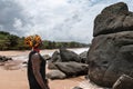 African woman standing on a beautiful beach with dark big stones and clean beach at the edge of the jungle in Axim Ghana West