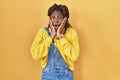 African woman standing over yellow background afraid and shocked, surprise and amazed expression with hands on face Royalty Free Stock Photo