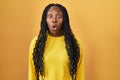 African woman standing over yellow background afraid and shocked with surprise expression, fear and excited face Royalty Free Stock Photo