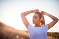 Woman standing in sunset day and binds a ponytail