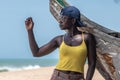 African woman with sunglasses and a backwards blue cap leaning against an old fishing boat in Cape coast Ghana West Africa Royalty Free Stock Photo