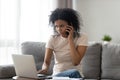 African woman talking on phone looking at computer screen