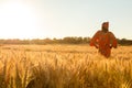 African woman traditional clothes stands in field of crops at sunset