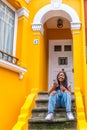 African woman using phone sitting on stairs outside a house