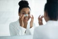 African woman looking in mirror applying cleansing nose strip Royalty Free Stock Photo