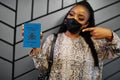 African woman wearing black face mask show Uganda passport in hand. Coronavirus in Africa country, border closure and quarantine,