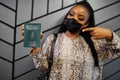 African woman wearing black face mask show Tunisia passport in hand. Coronavirus in Africa country, border closure and quarantine