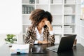 African Woman who is tired and overthinking from working with tablet and laptop at office Royalty Free Stock Photo