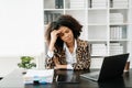 African Woman who is tired and overthinking from working with tablet and laptop at office Royalty Free Stock Photo