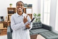 African woman working at psychology clinic cheerful with a smile on face pointing with hand and finger up to the side with happy