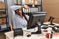 African woman working at small business ecommerce smiling cheerful playing peek a boo with hands showing face