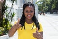 African woman in a yellow shirt in city showing thumb Royalty Free Stock Photo
