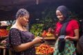 African woman shopping food stuff in a local market paying by doing mobile transfer via phone for a trader Royalty Free Stock Photo