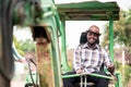 African worker driving heavy construction equipment backhoe with smile and happy