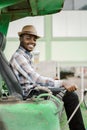 African worker driving heavy construction equipment backhoe with smile and happy