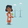 African worker of wind farm holding small plant.