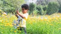 African 3 years old boy holding a big and heavy watering can, watering flowers garden on sunny day. Cute little child gardening, Royalty Free Stock Photo