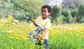 African 3 years old boy holding a big and heavy watering can, watering flowers garden on sunny day. Cute little child gardening, Royalty Free Stock Photo