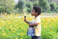 African 3 years old boy holding a big and heavy watering can, watering flowers garden on sunny day. Cute little child gardening, Royalty Free Stock Photo