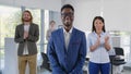 African young boss smiling at camera with diverse team applauding on background Royalty Free Stock Photo