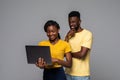 African young smiling loving couple standing over grey wall and using laptop computer Royalty Free Stock Photo