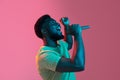 African young man's portrait on pink studio background in neon. Concept of human emotions, facial expression, youth