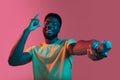 African young man's portrait on pink studio background in neon. Concept of human emotions, facial expression, youth