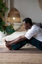 African young man sitting in paschimottanasana or Intense Dorsal Stretch pose, seated forward bend posture