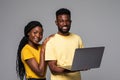 African young smiling loving couple standing over grey wall and using laptop computer Royalty Free Stock Photo