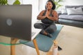 African young woman doing yoga virtual fitness class with laptop at home Royalty Free Stock Photo
