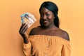 African young woman holding canadian dollars looking positive and happy standing and smiling with a confident smile showing teeth Royalty Free Stock Photo