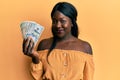 African young woman holding dollars looking positive and happy standing and smiling with a confident smile showing teeth Royalty Free Stock Photo
