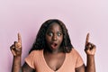 African young woman pointing up with fingers afraid and shocked with surprise and amazed expression, fear and excited face