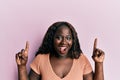 African young woman pointing up with fingers smiling and laughing hard out loud because funny crazy joke Royalty Free Stock Photo