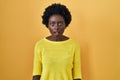 African young woman standing over yellow studio afraid and shocked with surprise and amazed expression, fear and excited face Royalty Free Stock Photo