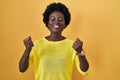 African young woman standing over yellow studio excited for success with arms raised and eyes closed celebrating victory smiling Royalty Free Stock Photo