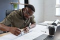 Afro-American architect working in office with blueprints.Engineer inspect architectural plan, sketching a construction Royalty Free Stock Photo