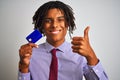 Afro american businessman with dreadlocks holding credit card over isolated white background happy with big smile doing ok sign, Royalty Free Stock Photo
