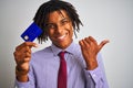 Afro american businessman with dreadlocks holding credit card over isolated white background pointing and showing with thumb up to Royalty Free Stock Photo