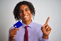 Afro american businessman with dreadlocks holding credit card over isolated white background very happy pointing with hand and Royalty Free Stock Photo