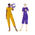 Afro american and caucasian short-haired girls in fashionable modern jumpsuits stand together talking