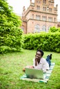 Afro american college student lying down on the grass working on laptop at campus. University. Royalty Free Stock Photo